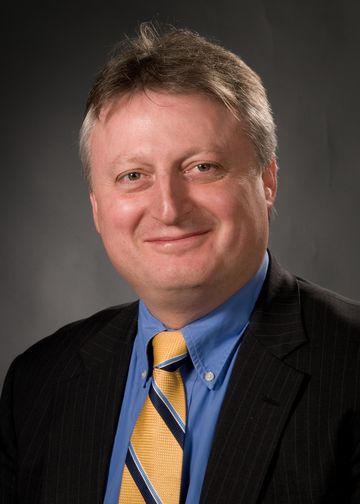 John Di Capua, MD, wearing a blue shirt, and gold and blue tie
